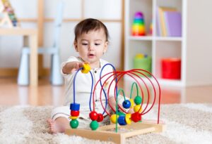 7-miesięczne niemowlę bawi się kolorowymi zabawkami, poznaje różnorodne tekstury i kształty.